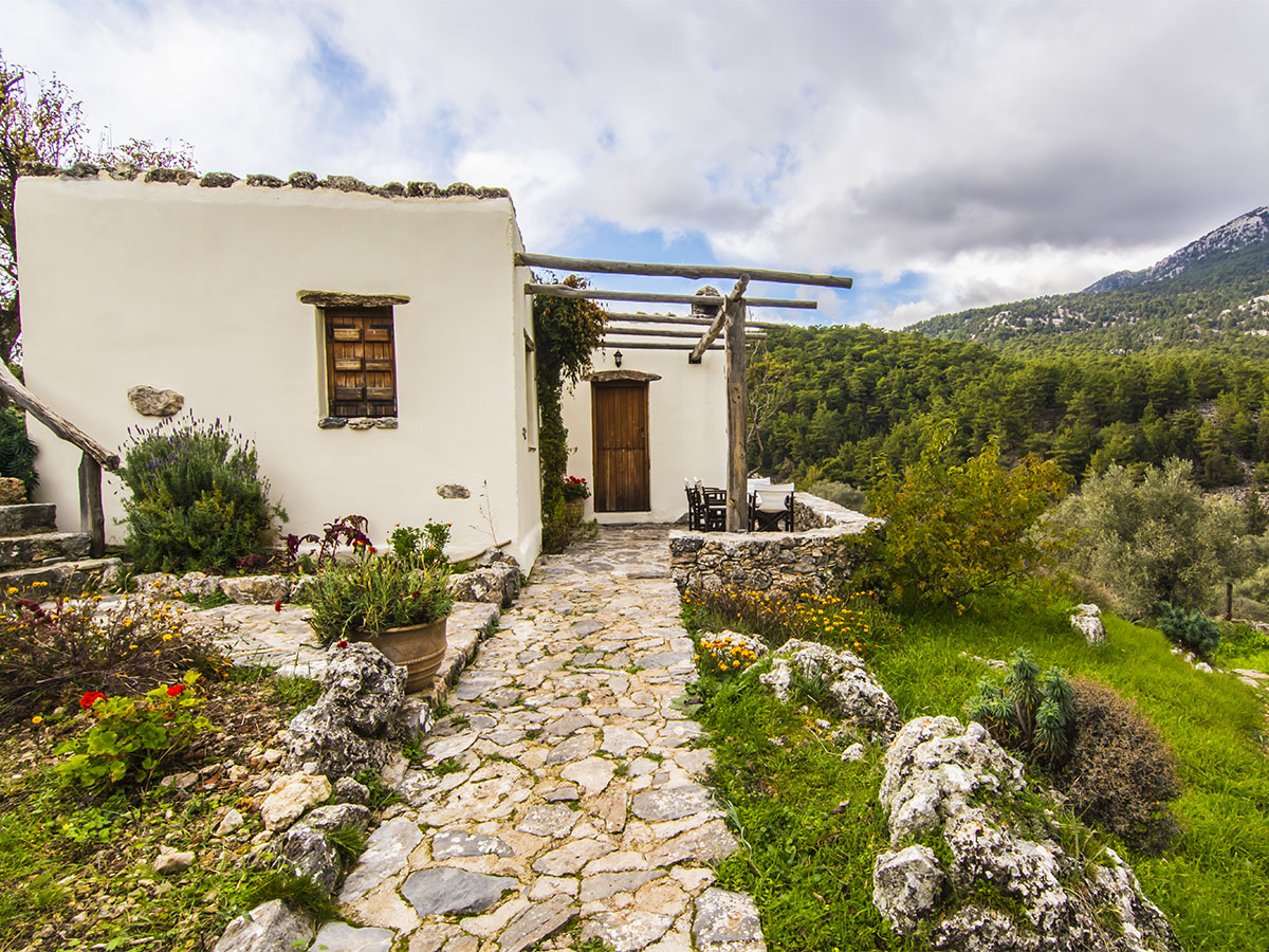 Alonia Guest House stone building with pergola terrace, White Mountains behind