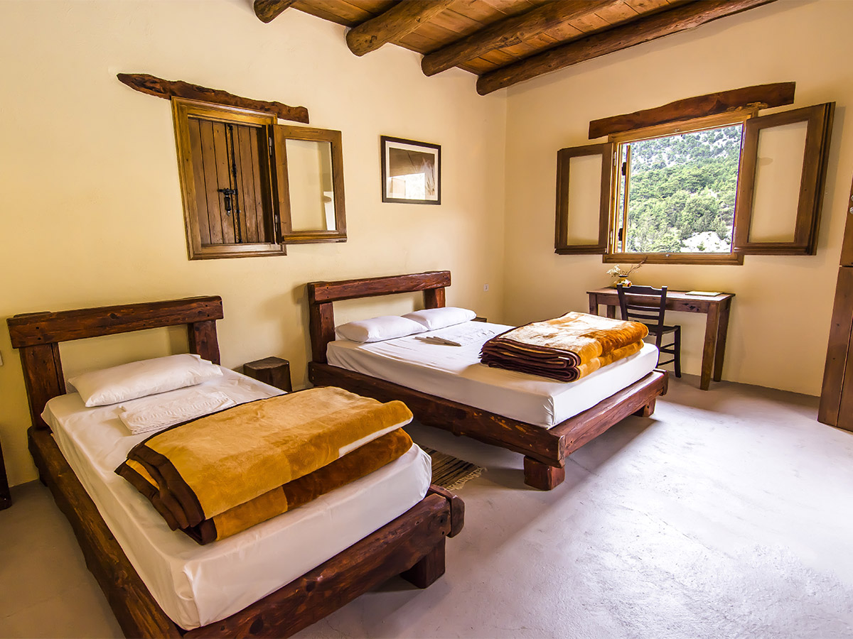 Twin and double beds with handcrafted wooden frames and mountain-facing desk
