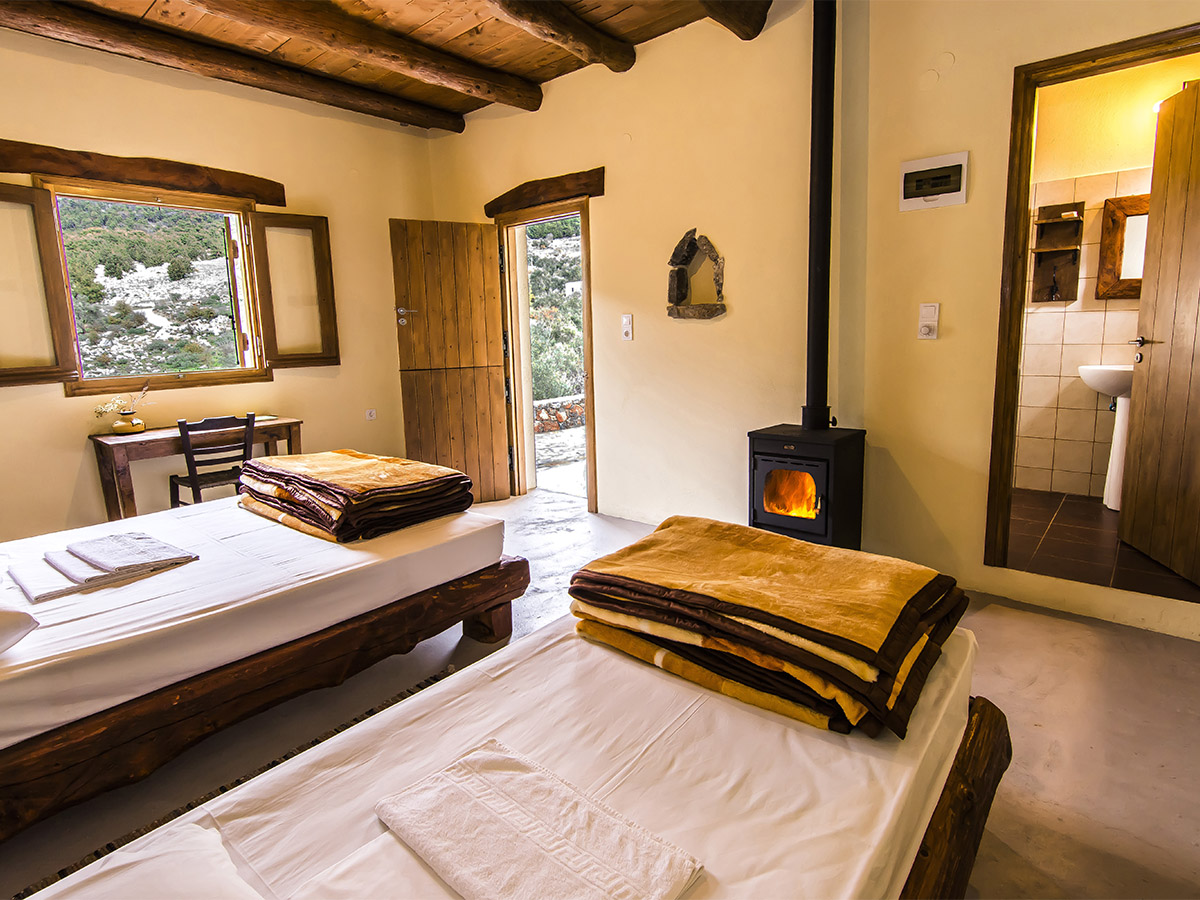 Twin room at Alonia with lit wood-burning stove and private ensuite bathroom